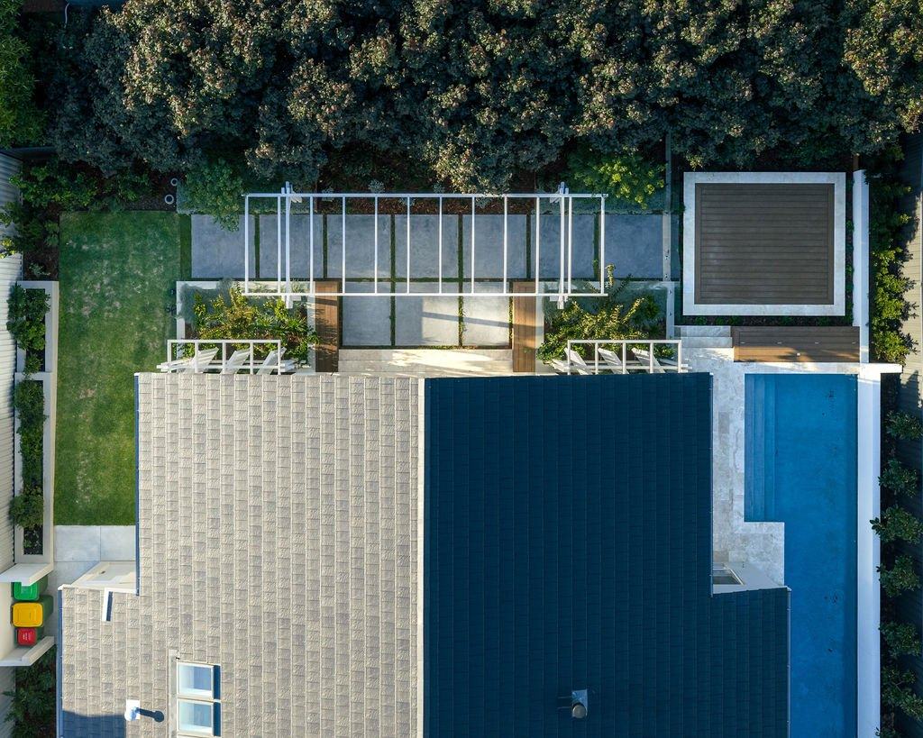 Overhead view of the rear garden: pergola, paving, lawn, deck and lap pool