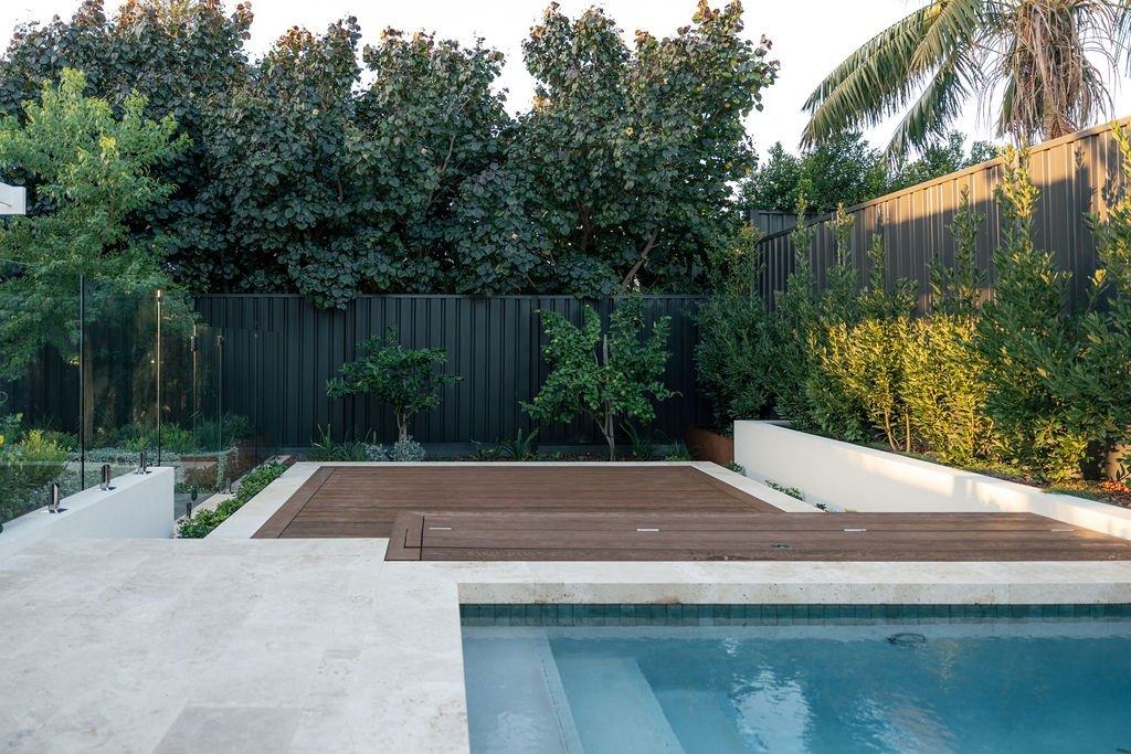 Lap pool with travertine coping beside a rendered planter wall, Anugraha House