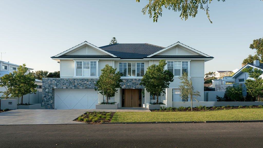 Anugraha House: weatherboard residence with stone cladding, timber entry doors, rendered planters and young trees