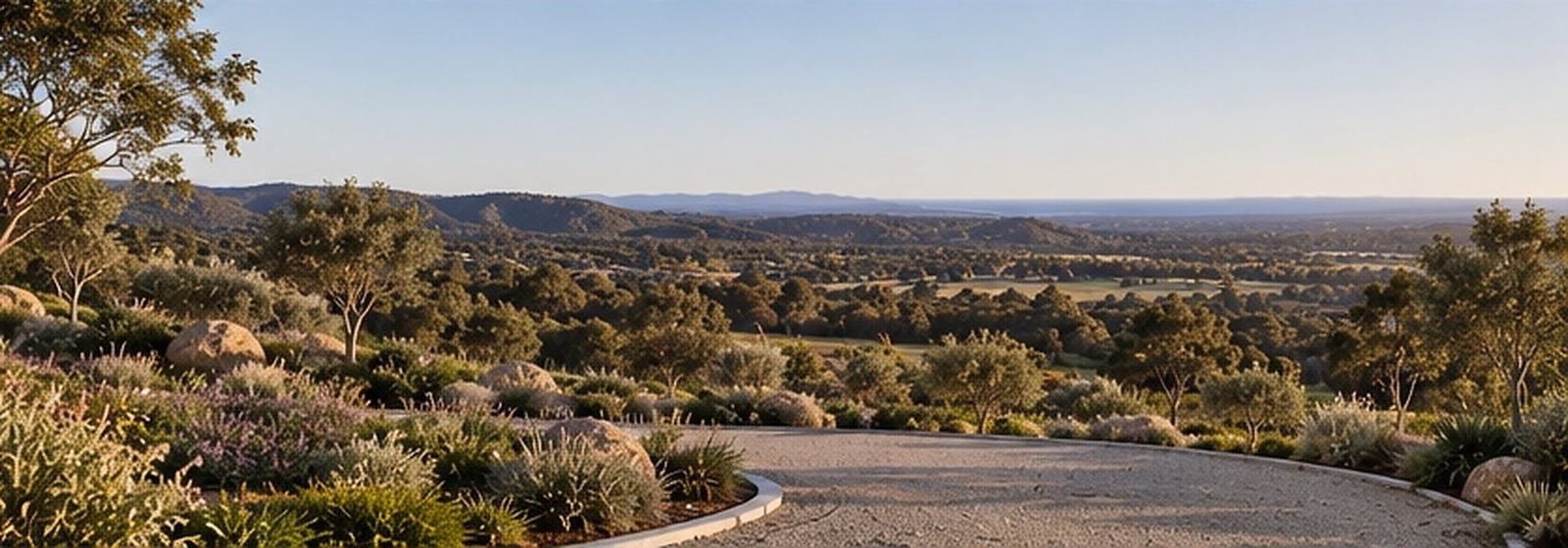 Gravel path and planted beds framing a wide view over the valley to distant hills