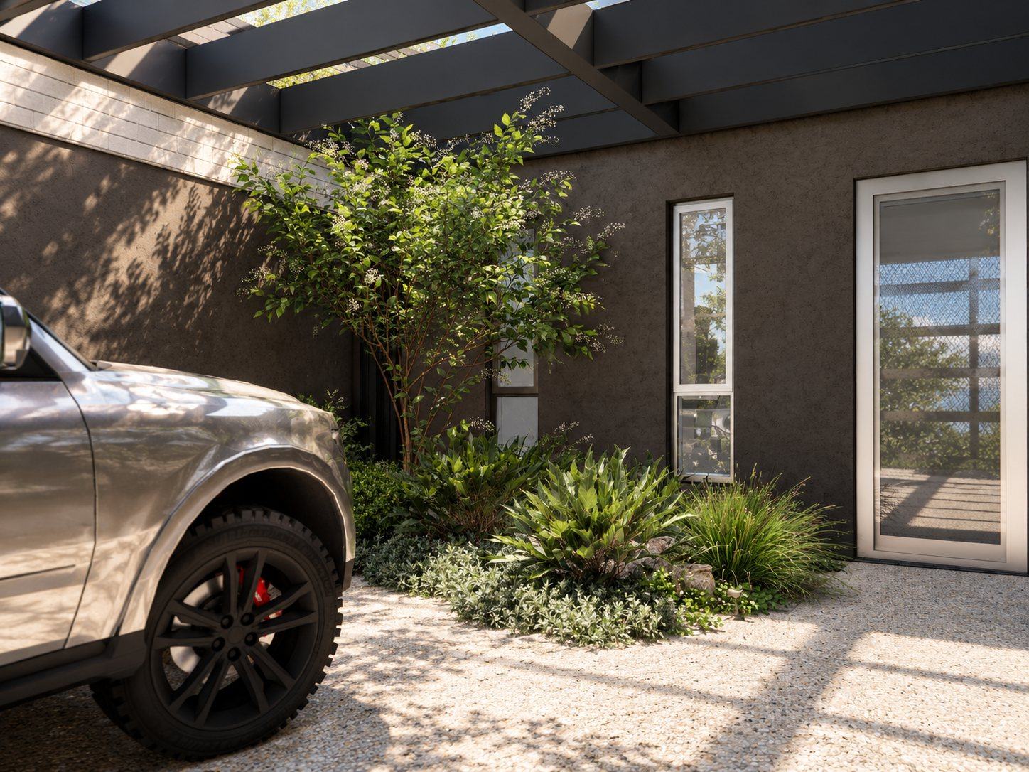 Feature tree and layered shrubs in a planted pocket beside the carport